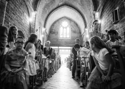Invités et enfants tournés vers l’allée centrale lors d’une cérémonie religieuse de mariage à l’église de Frontignan – photographe mariage Mathis Vision