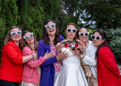 La mariée entourée de ses invitées portant des lunettes cœur lors d’un mariage festif - photographe mariage Mathis Vision